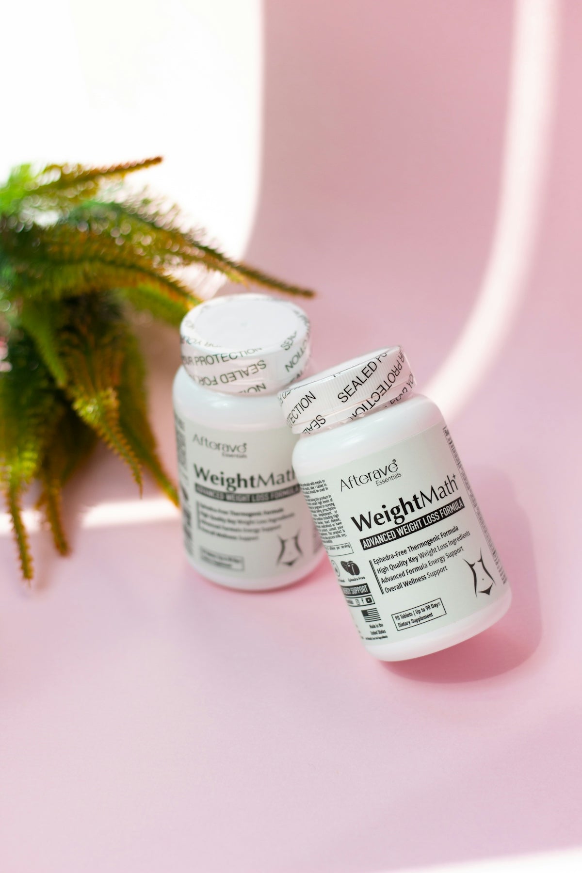 Two bottles of medicine sitting on a pink surface