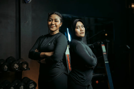 Two women stand together confidently in a gym.