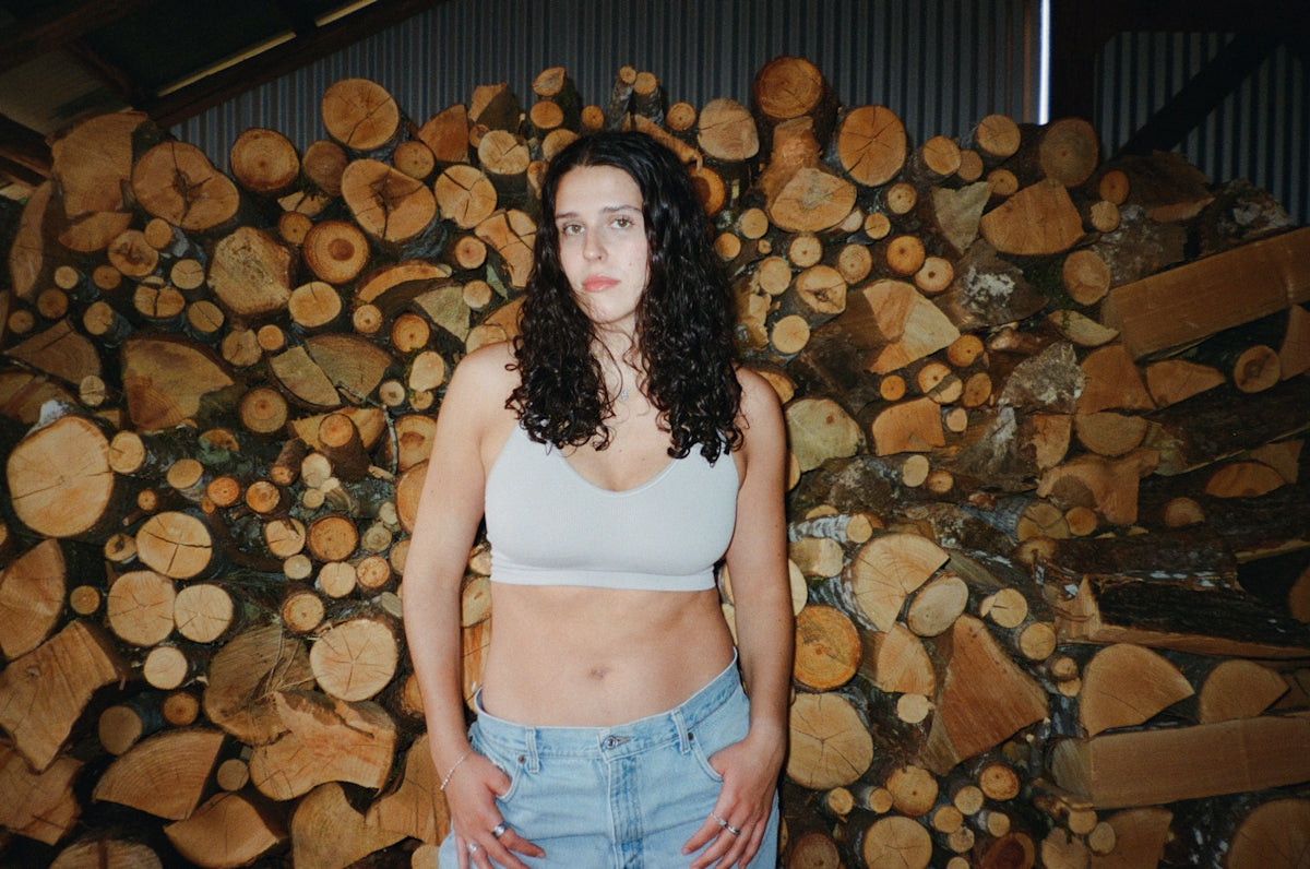 Woman stands against a wall of firewood
